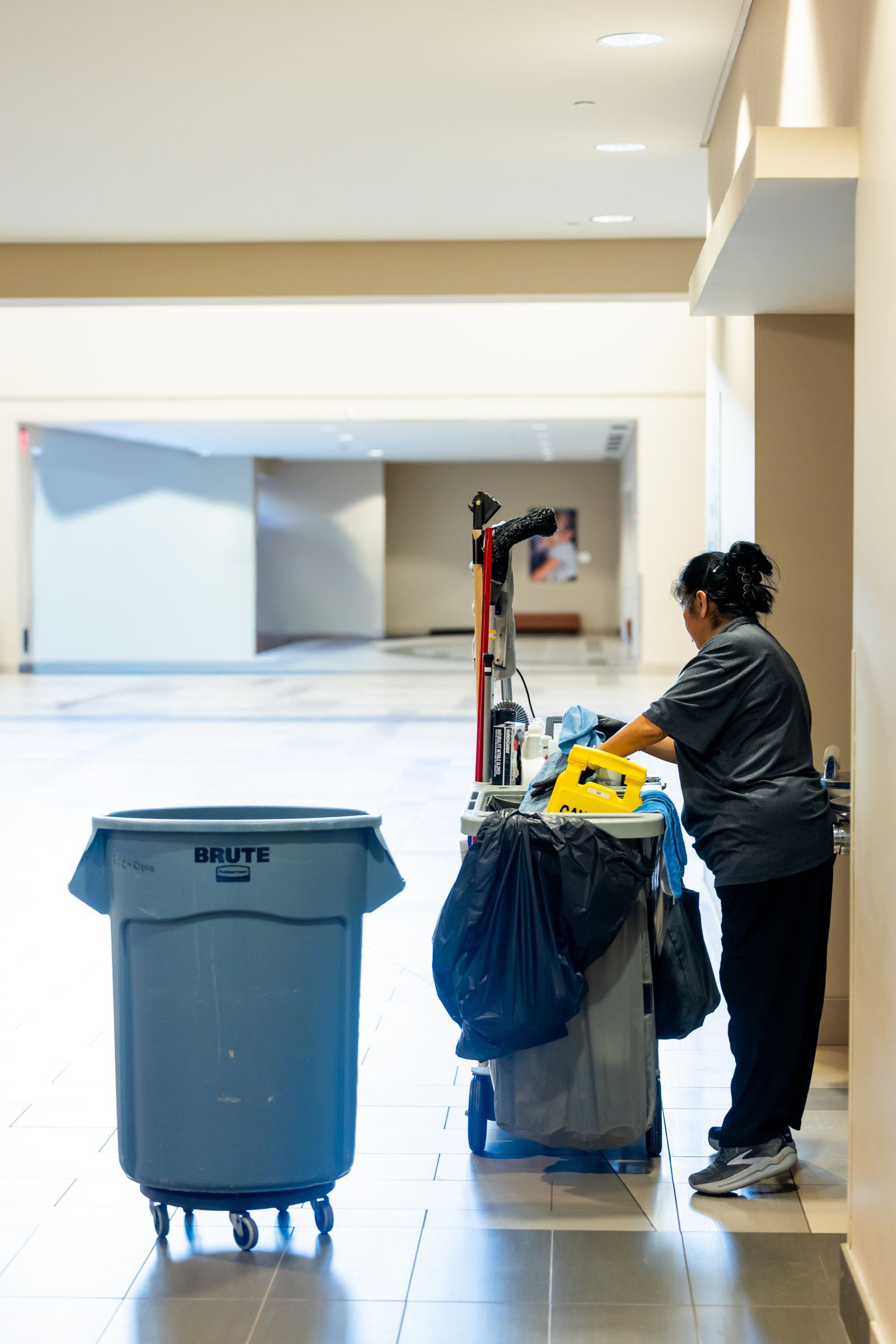 A cleaner with a cleaning trolley in a commercial building corridor